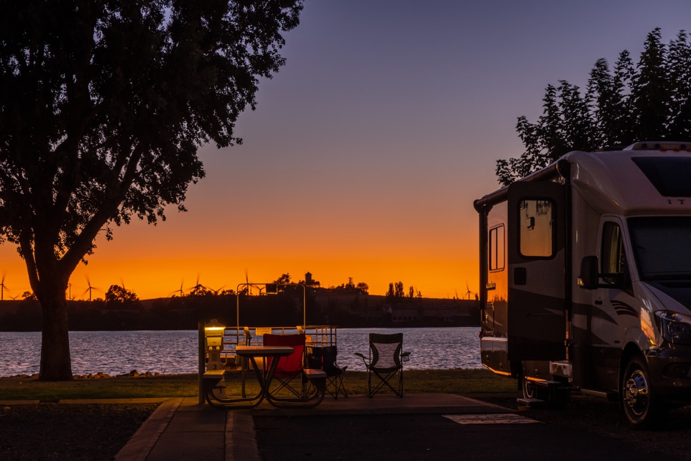 RV parked at a lakeside campsite during a vibrant sunset