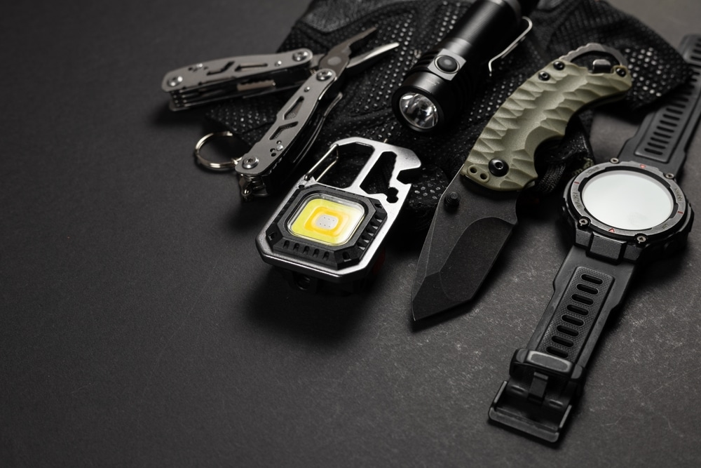 Collection of everyday carry survival gear including a knife, multi-tool, and flashlights