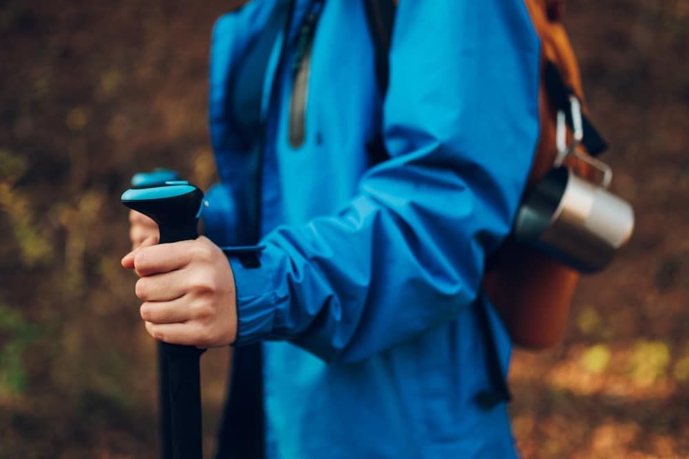 Close-up of a hiker in a blue jacket holding trekking poles