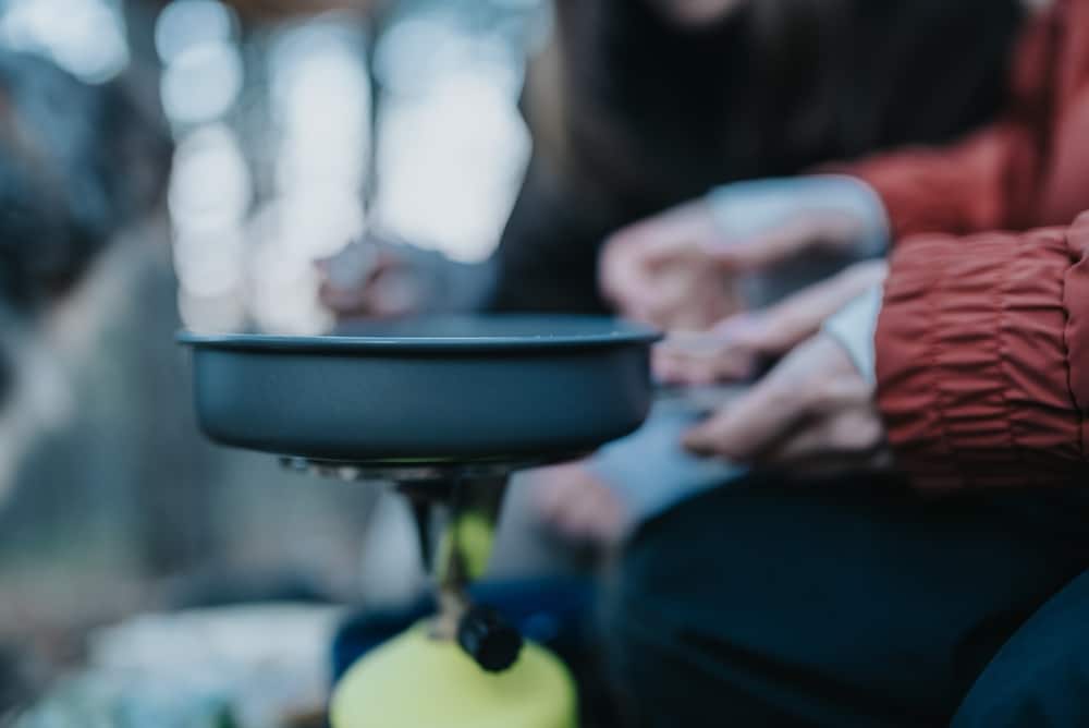Close-up of food cooking in a pan on a portable camping stove outdoors